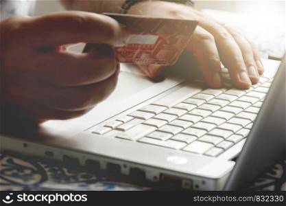 male hand holding a credit card during an internet payment transaction. Concept of e-commerce and online shopping.