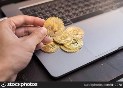 male hand holding bitcoin on a laptop background.
