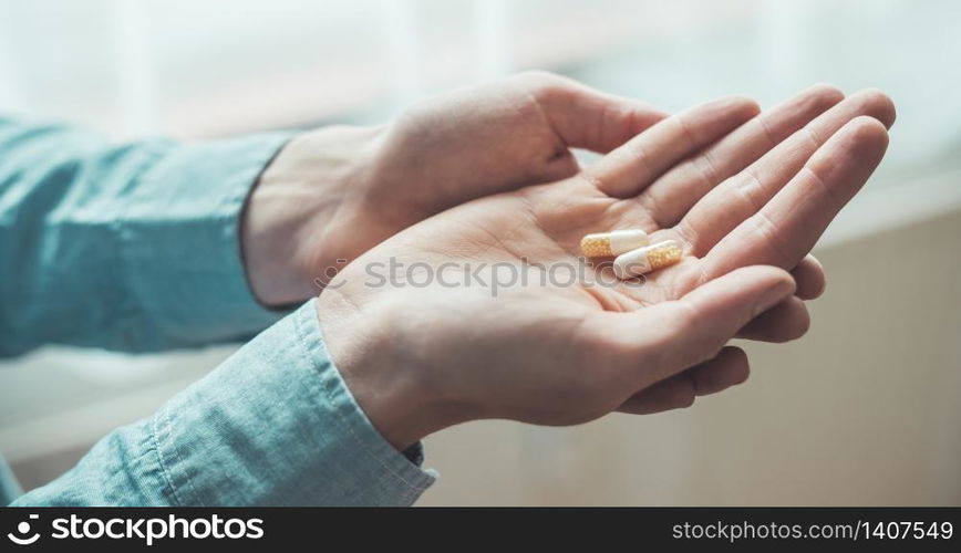 Male hand holding drug or vitamin pill in