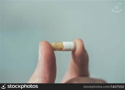 Male hand holding drug or vitamin pill in