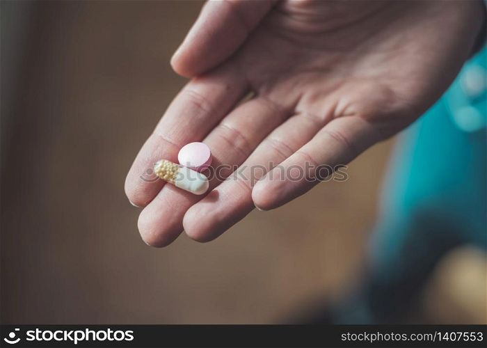 Male hand holding drug or vitamin pill in