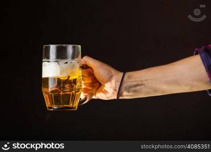Male hand holding mug of beer dark background