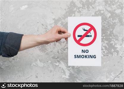 male hand holding paper with no smoking sign text weathered wall . Resolution and high quality beautiful photo. male hand holding paper with no smoking sign text weathered wall . High quality and resolution beautiful photo concept