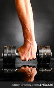 male hand is holding metal barbell on dark gray background