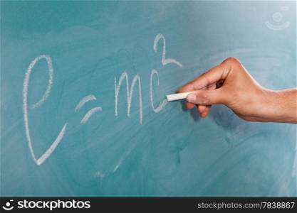 Male hand is writing Einstein&rsquo;s Formula E=mc2 on a blackboard