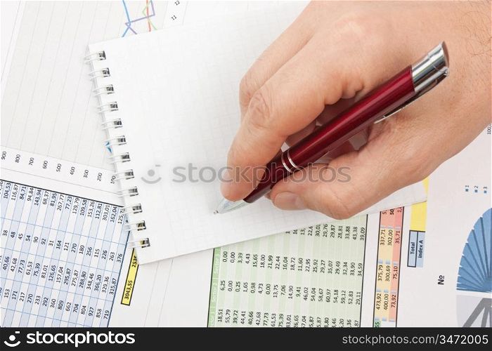 Male hand is writing in business document lying on the table