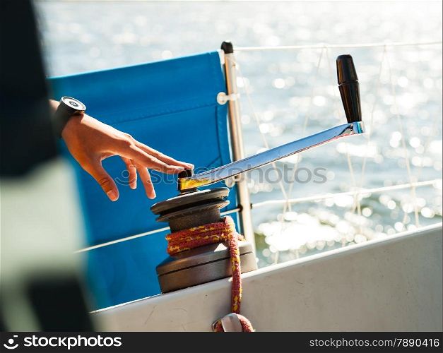 Male hand on winch capstan with rope on sailing boat. Yachting yacht in blue baltic sea sunny day summer vacation. Tourism luxury lifestyle.