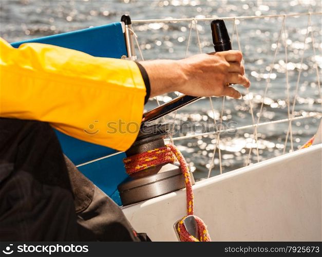 Male hand on winch capstan with rope on sailing boat. Yachting yacht in blue baltic sea sunny day summer vacation. Tourism luxury lifestyle.