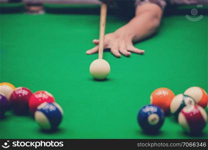 Male hand playing Snooker or Pool game on green table.