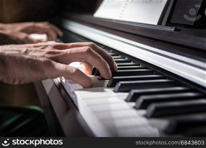 Male hand playing the keys of piano