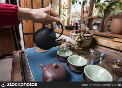Male hand pouring tea into tea cups in store