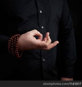 male hand shows mudra on a dark background, concept of meditation