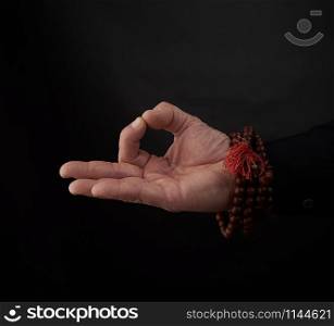 male hand shows the mudra of Knowledge on a black background, the concept of relaxation and meditation