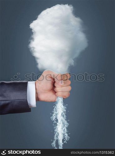 Male hand squeezing a cloud over grey background. Cloud in a human hand