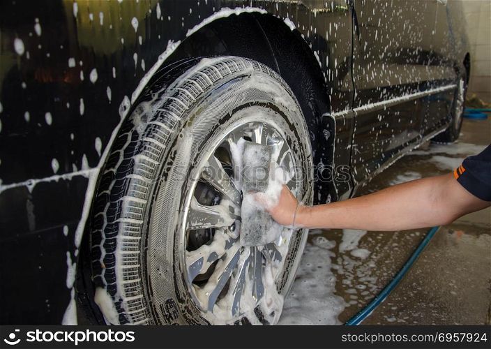 male hand washing wheel car.. Car Wash Foam wheel