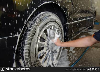 male hand washing wheel car.. Car Wash Foam wheel