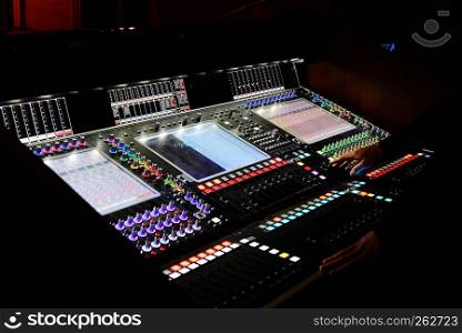 Male hands are on a professional digital mixing console for sound control in a recording studio