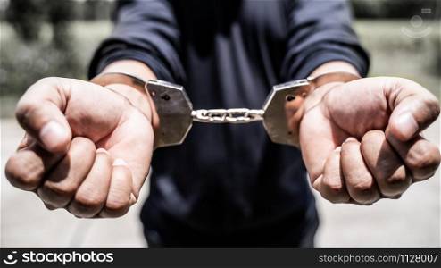 Male hands arrested with handcuffs in Criminal concept.