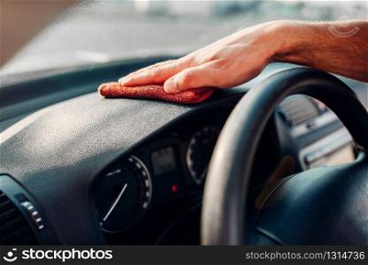Male hands cleans auto, car dashboard polishing on carwash station. Man rubbing vehicle torpedo with polish.. Male hands cleans auto, car dashboard polishing