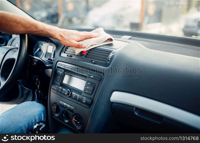 Male hands cleans auto, car dashboard polishing on carwash station. Man rubbing vehicle torpedo with polish.. Male hands cleans auto, car dashboard polishing