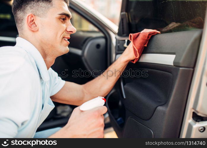 Male hands cleans auto on carwash station. Man rubbing vehicle inside. Male hands cleans auto