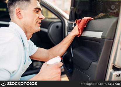 Male hands cleans auto on carwash station. Man rubbing vehicle inside. Male hands cleans auto