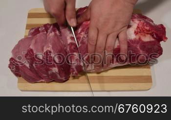 Male hands cutting fresh pork meat on wooden cutting board