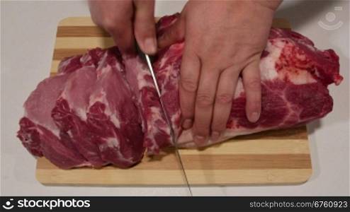 Male hands cutting fresh pork meat on wooden cutting board