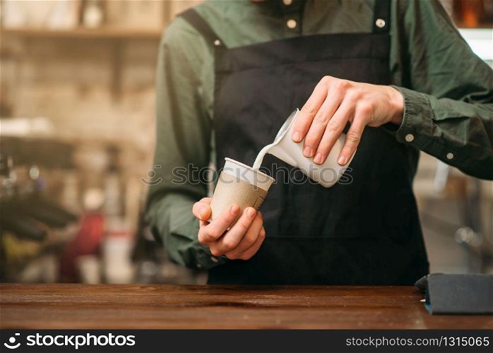 Male hands fills in a cup of milk. Blur background.