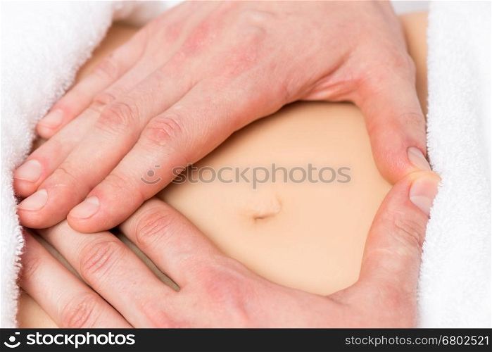 male hands in a heart shape on the abdomen of a pregnant woman close-up