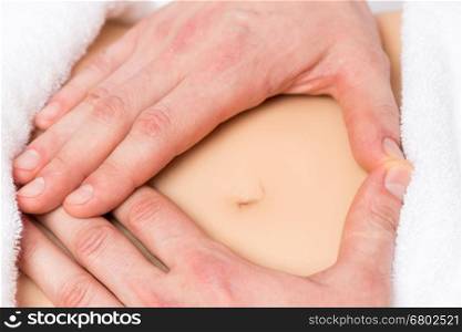 male hands in a heart shape on the abdomen of a pregnant woman close-up
