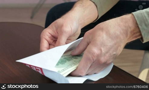 Male hands pulling and counting money from an envelope