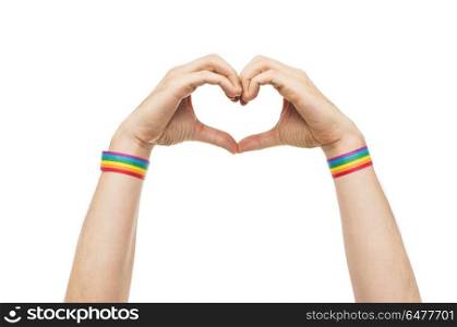 male hands with gay pride wristbands showing heart. lgbt, same-sex love and homosexual relationships concept - close up of male hands with gay pride rainbow awareness wristbands showing heart gesture