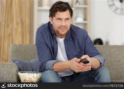 male hands with tv remote control and popcorn