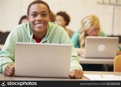 Male High School Student At Desk In Class Using Laptop