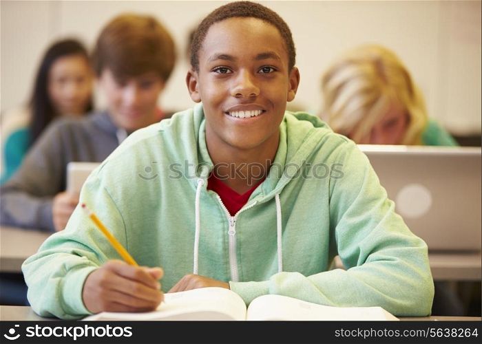 Male High School Student Studying At Desk In Classroom