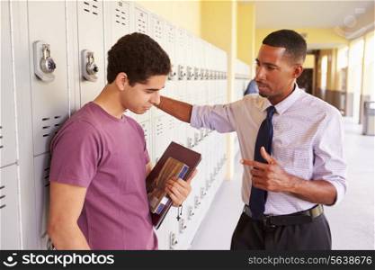 Male High School Student Talking To Teacher By Lockers