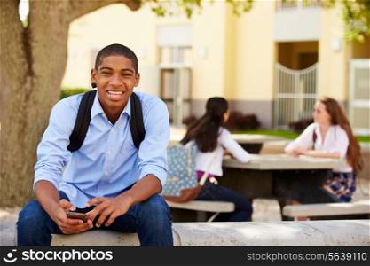 Male High School Student Using Phone On School Campus