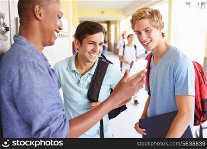 Male High School Students By Lockers Looking At Mobile Phone