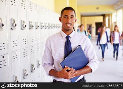 Male High School Teacher Standing By Lockers