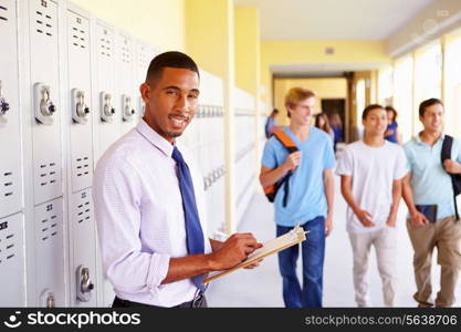 Male High School Teacher Standing By Lockers