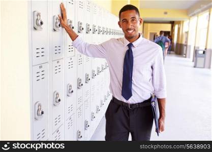 Male High School Teacher Standing By Lockers
