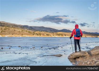 male hiker at a shore of frozen Horsetooth Reservoir near Fort Collins, Colorado - winter hiking concept