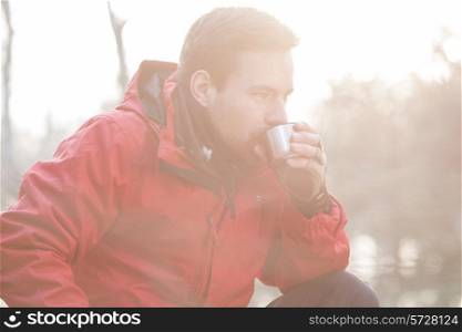 Male hiker drinking coffee in forest