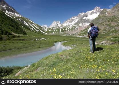Male hiker enjoying the view over the beautiful landscape of Lac Combal, Val Veny, Courmayeur, Italy