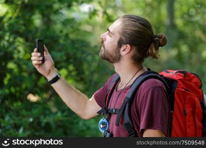 male hiker is looking to his phone