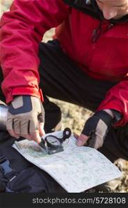 Male hiker using compass and map in forest