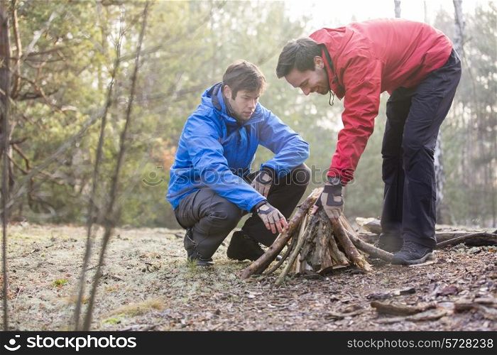 Male hikers arranging firewood in forest