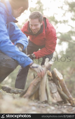 Male hikers lighting bonfire in forest