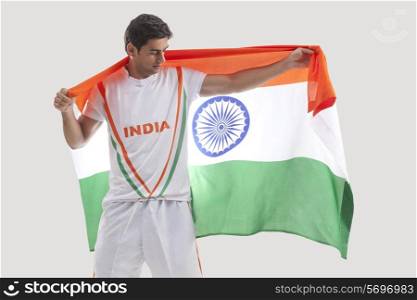 Male hockey player celebrating victory with Indian flag against gray background